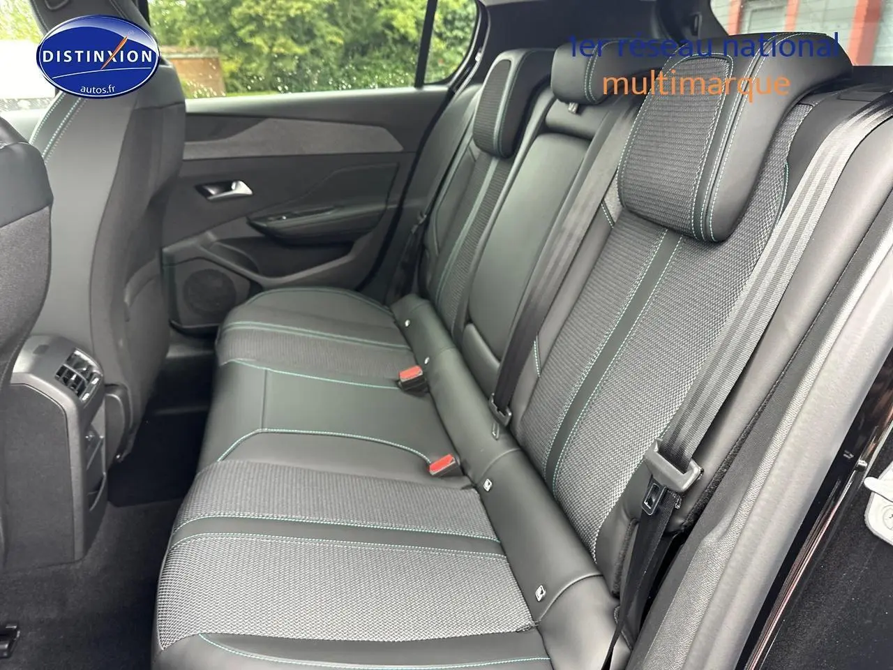 Vue intérieure sur la banquette arrière droite de la Peugeot 308 noire avec sellerie tissu et cuir aux surpiqûres vertes.