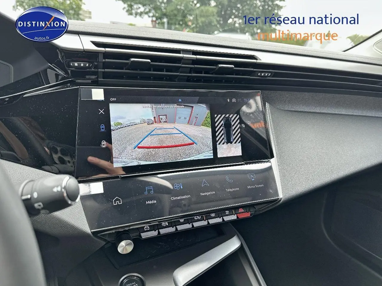 Vue rapprochée de l'écran tactile central affichant la caméra de recul dans l'habitacle d'une Peugeot 308 noire.