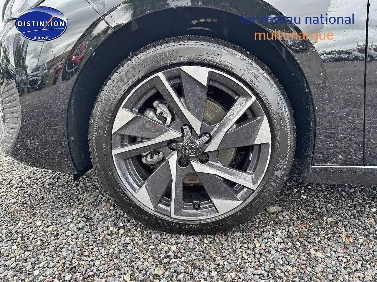 Gros plan sur la jante alu noire et grise du côté avant gauche d'une Peugeot 308 noire 2025.