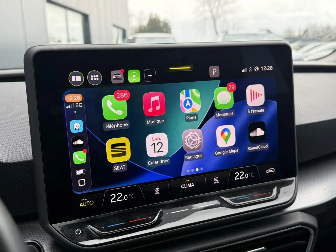 Écran tactile central du tableau de bord du SEAT Leon 2025 affichant les applications connectées et la climatisation à 22°C.