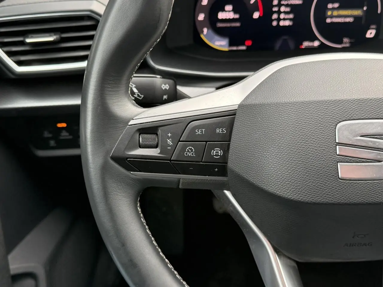 Gros plan sur le volant cuir multifonction de la SEAT Leon 1.5 TSI 115 Style, avec commandes de régulateur de vitesse.