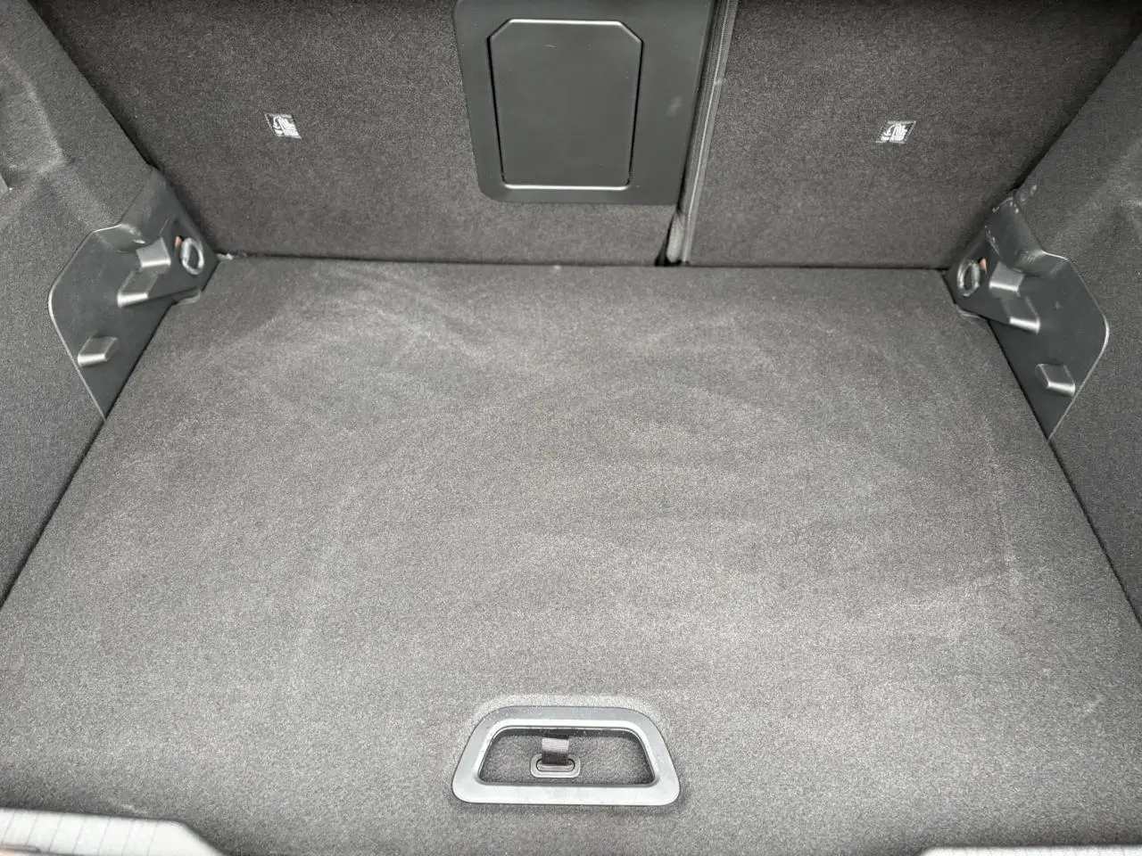 Vue plongeante sur le coffre spacieux et tapissé de tissu gris foncé du Citroën C4 Hybrid 2025.