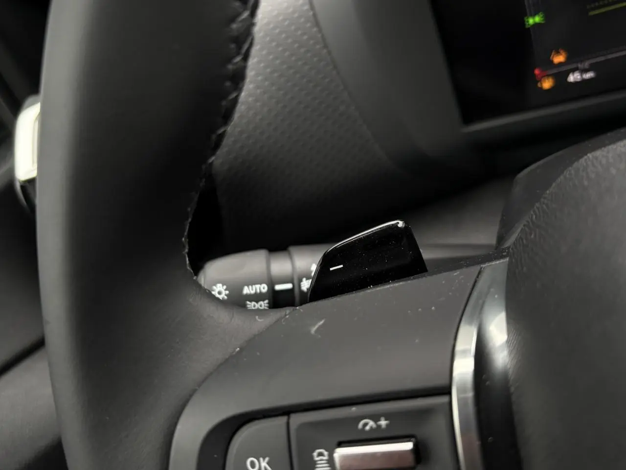 Gros plan sur le volant noir de la Citroën C4 Hybrid 2025, avec palettes de changement de rapports visibles.