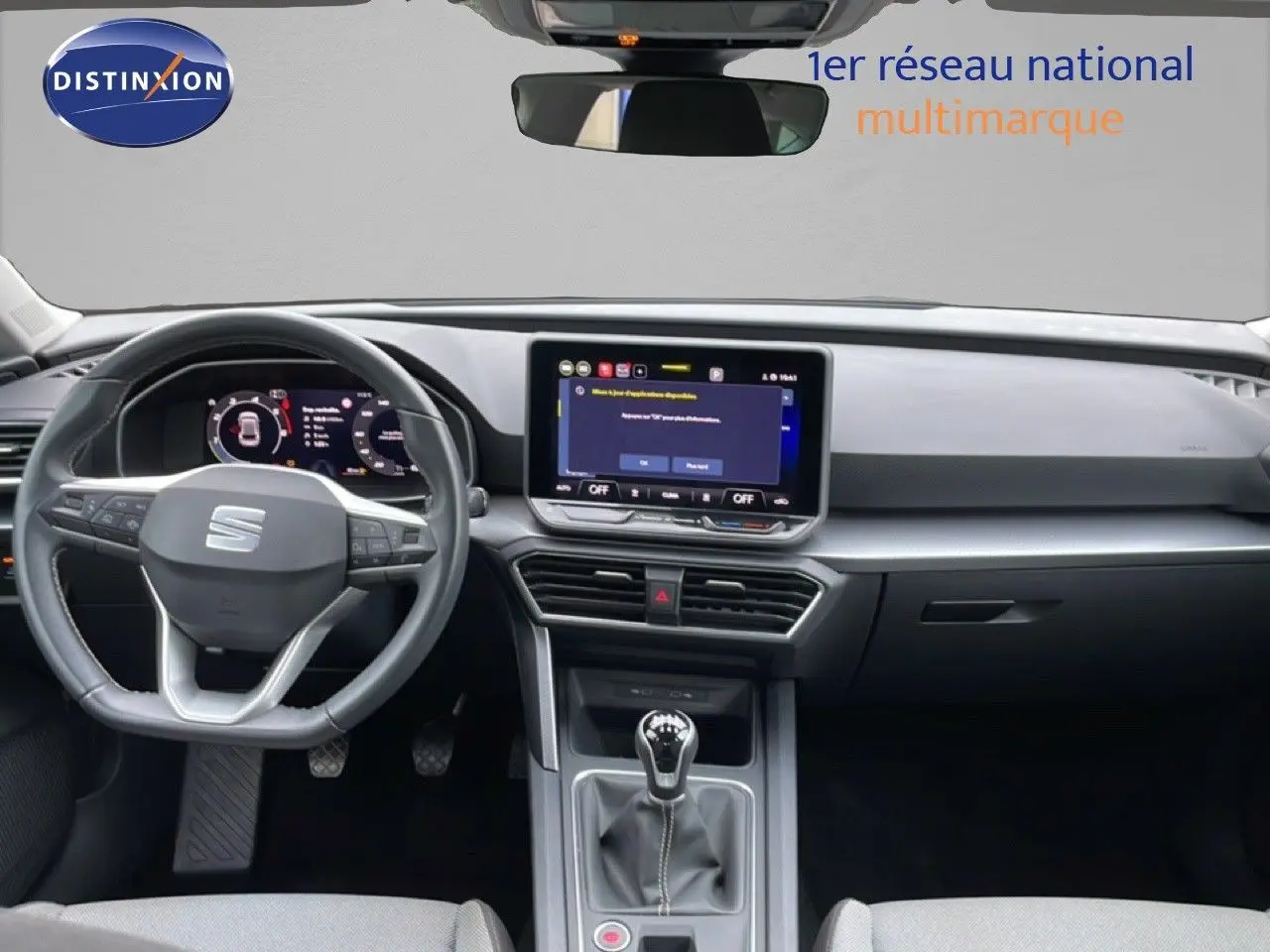 Vue intérieure frontale du tableau de bord gris noir de la SEAT LEON 2025 avec écran tactile et boîte manuelle.