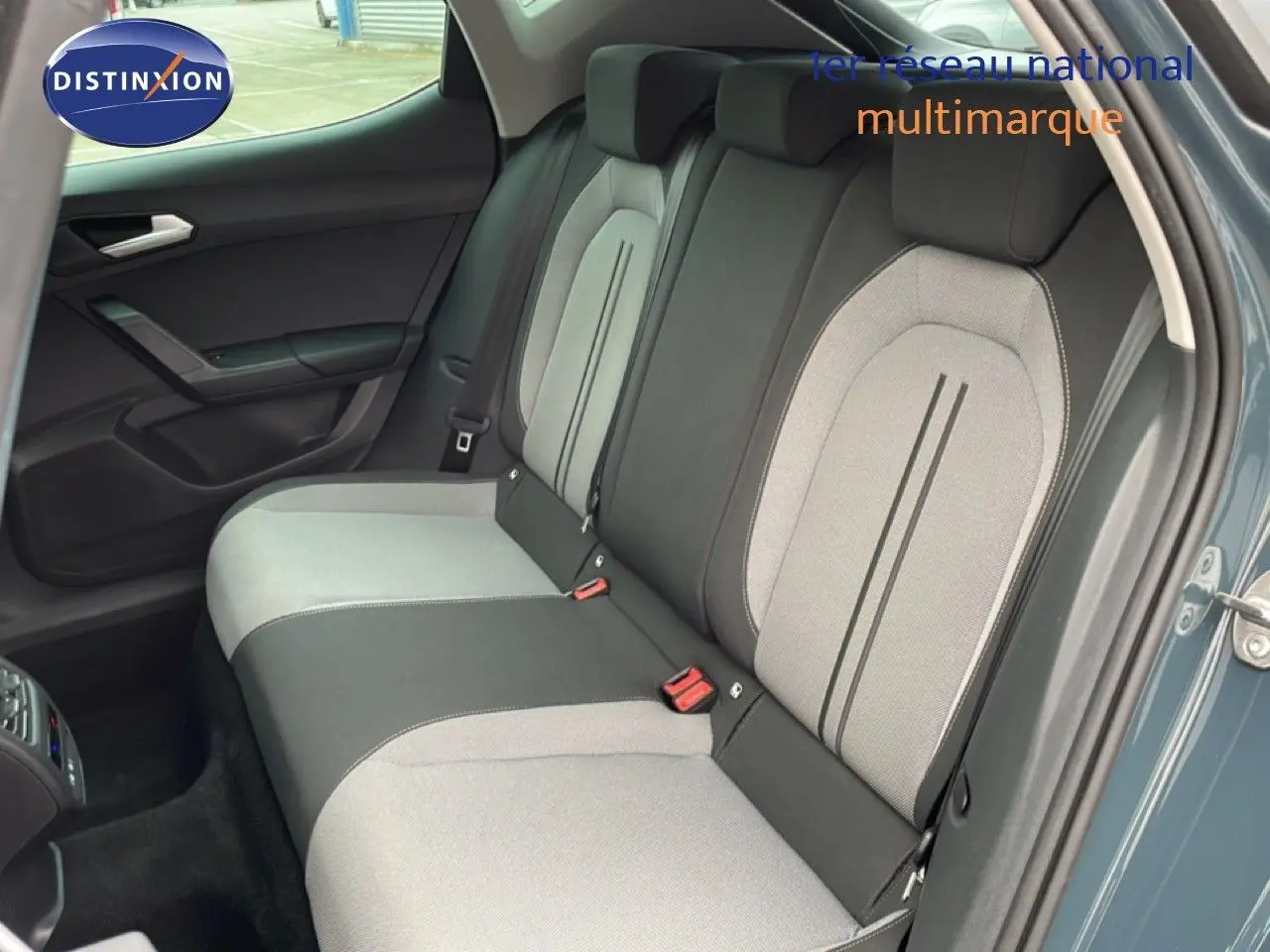 Vue intérieure côté arrière droit du SEAT LEON 2025 gris magnétique, montrant les sièges arrière bi-ton gris clair et foncé.