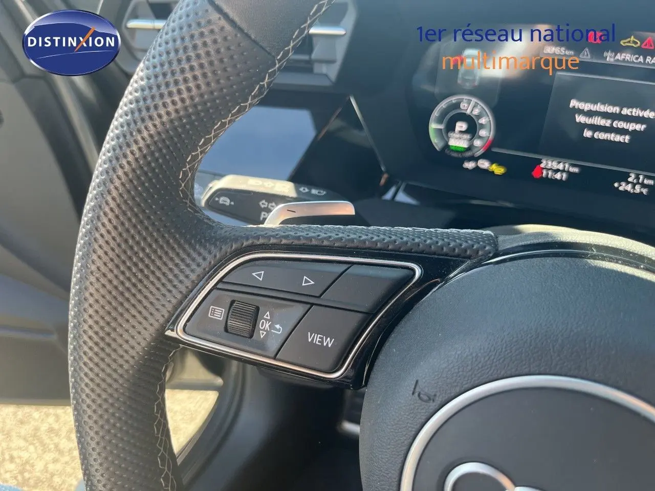 Gros plan sur le volant perforé et les commandes multifonctions de l'Audi A3 Sportback 40 TFSIe gris Daytona, intérieur noir.