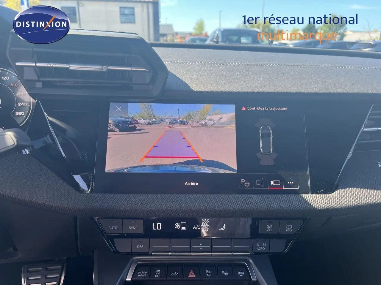 Vue intérieure du tableau de bord de l'Audi A3 Sportback gris Daytona, écran affichant la caméra de recul et les commandes climatiques.
