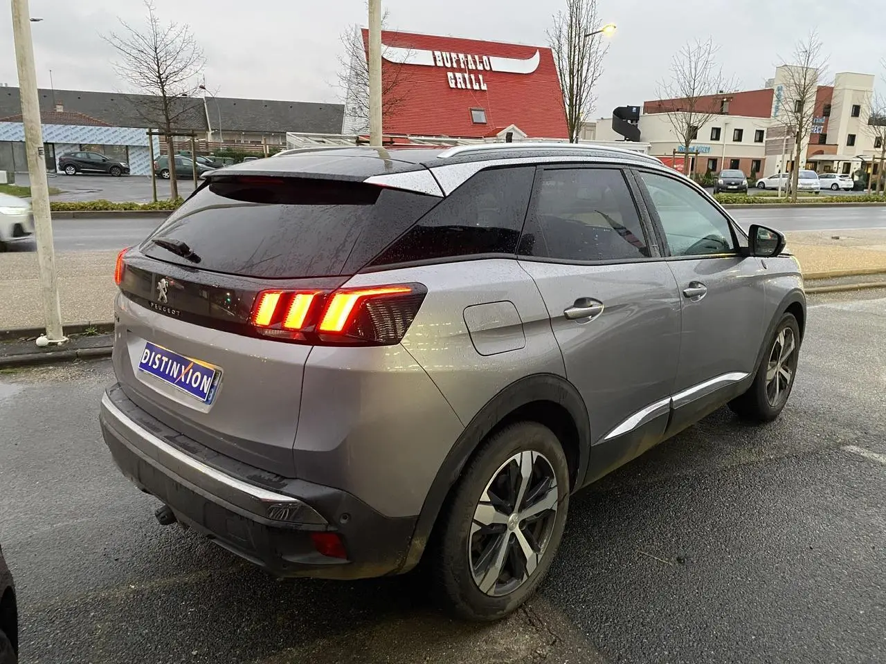 Peugeot 3008 gris Artense vue 3/4 arrière droit, feux arrière allumés et toit noir Perla Nera.