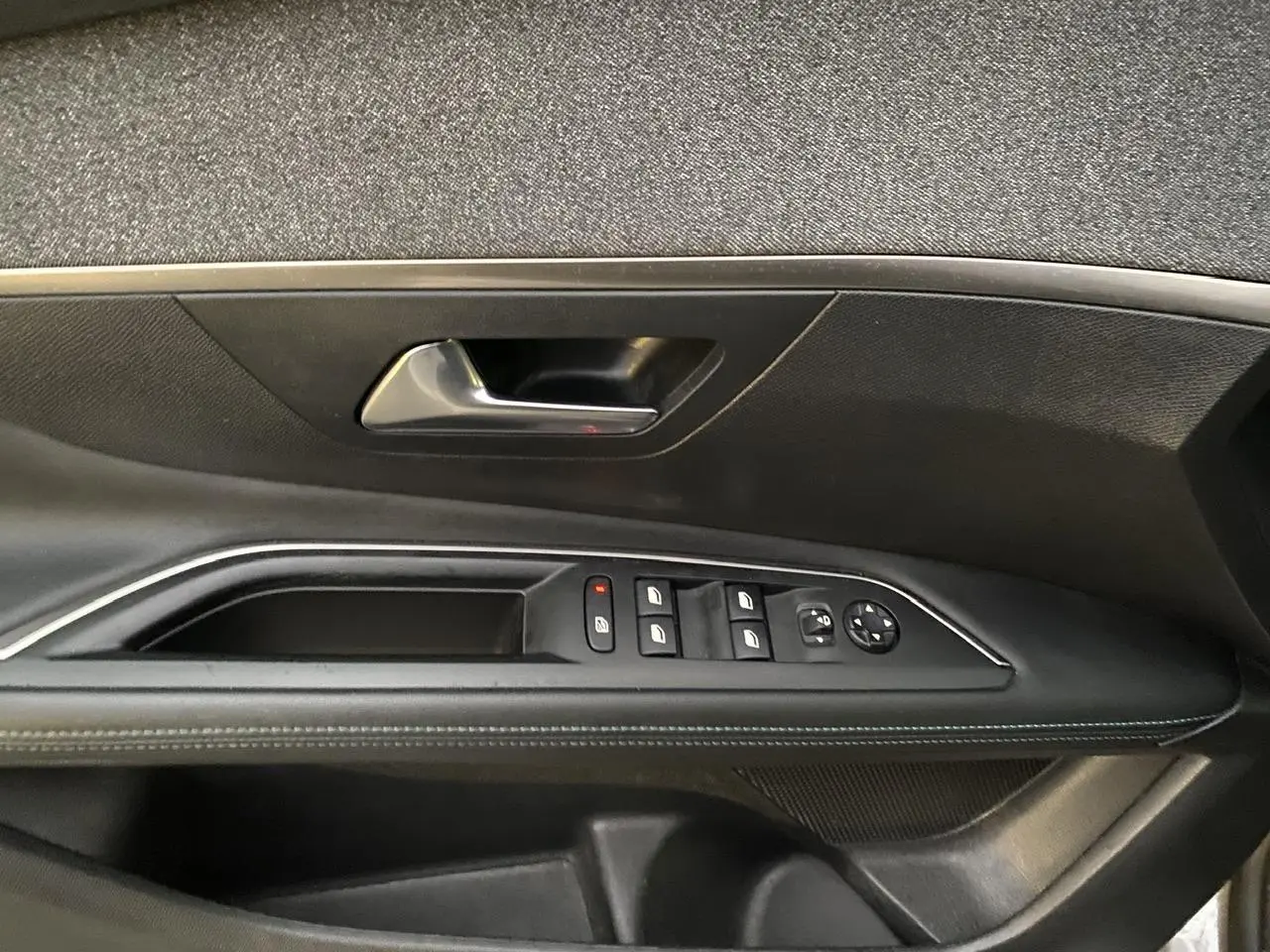 Détail de la porte côté conducteur du Peugeot 3008 gris Artense, avec commandes des vitres et rétroviseurs.