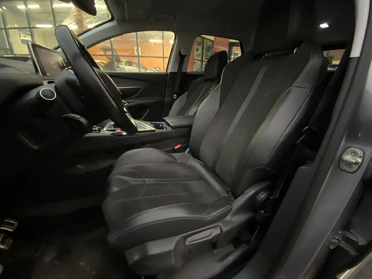 Vue intérieure côté conducteur du Peugeot 3008 gris Artense, mettant en valeur les sièges noirs et le tableau de bord.