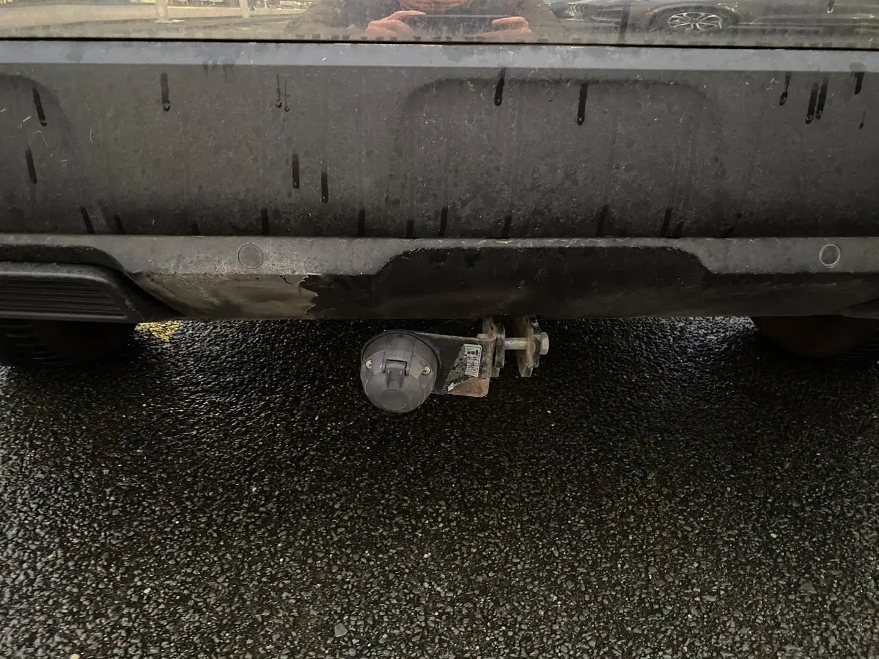 Prise électrique d'attelage sous le pare-chocs arrière d'un Peugeot 3008 gris Artense, vue centrée en gros plan.