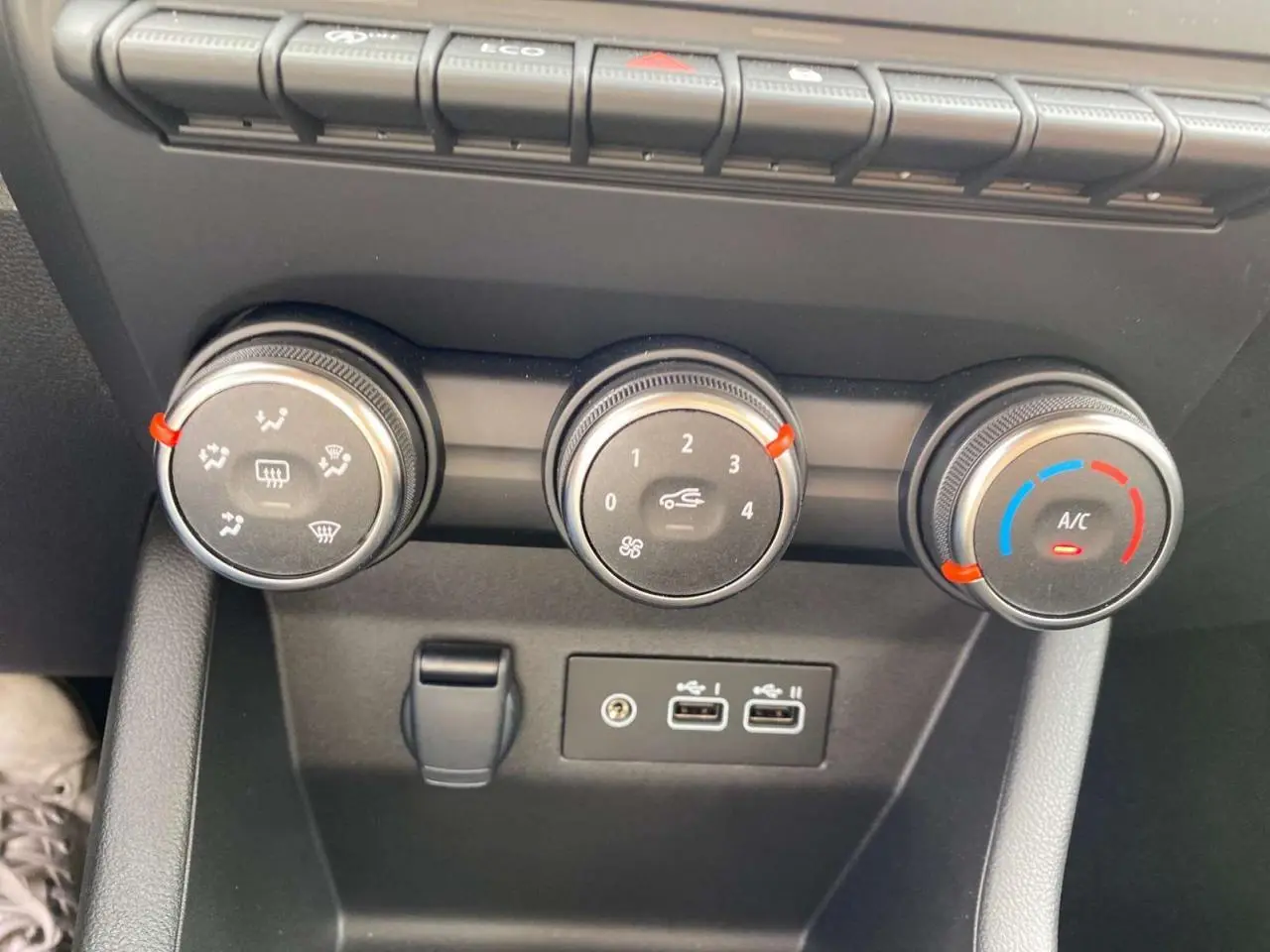 Gros plan sur les commandes de climatisation et ports USB du tableau de bord de la Renault Clio gris Rafale 2025.