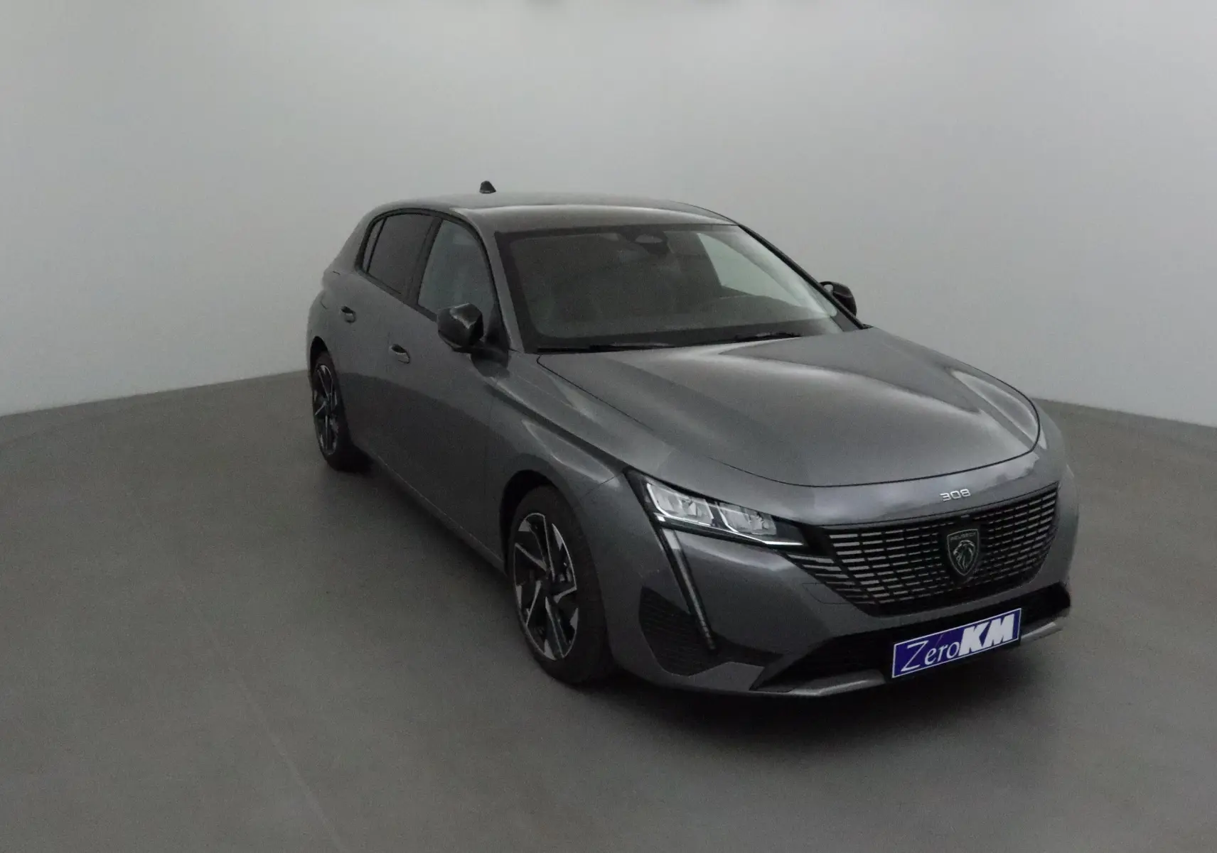 Peugeot 308 gris Sellenium vue 3/4 avant droit, avec calandre noire et phares LED distinctifs.