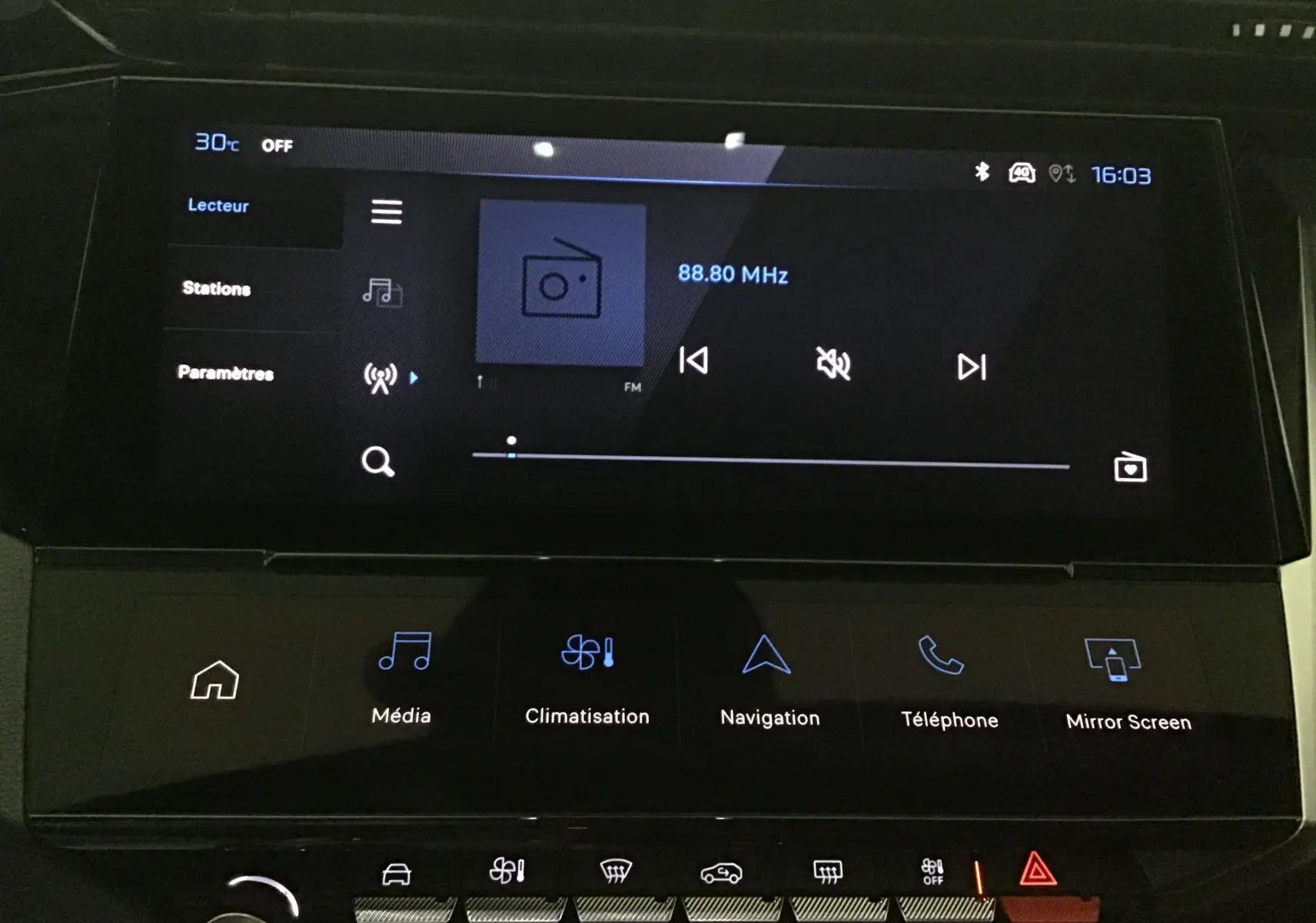 Écran tactile central de la Peugeot 308 2025 affichant la radio FM et les commandes multimédia et climatisation.