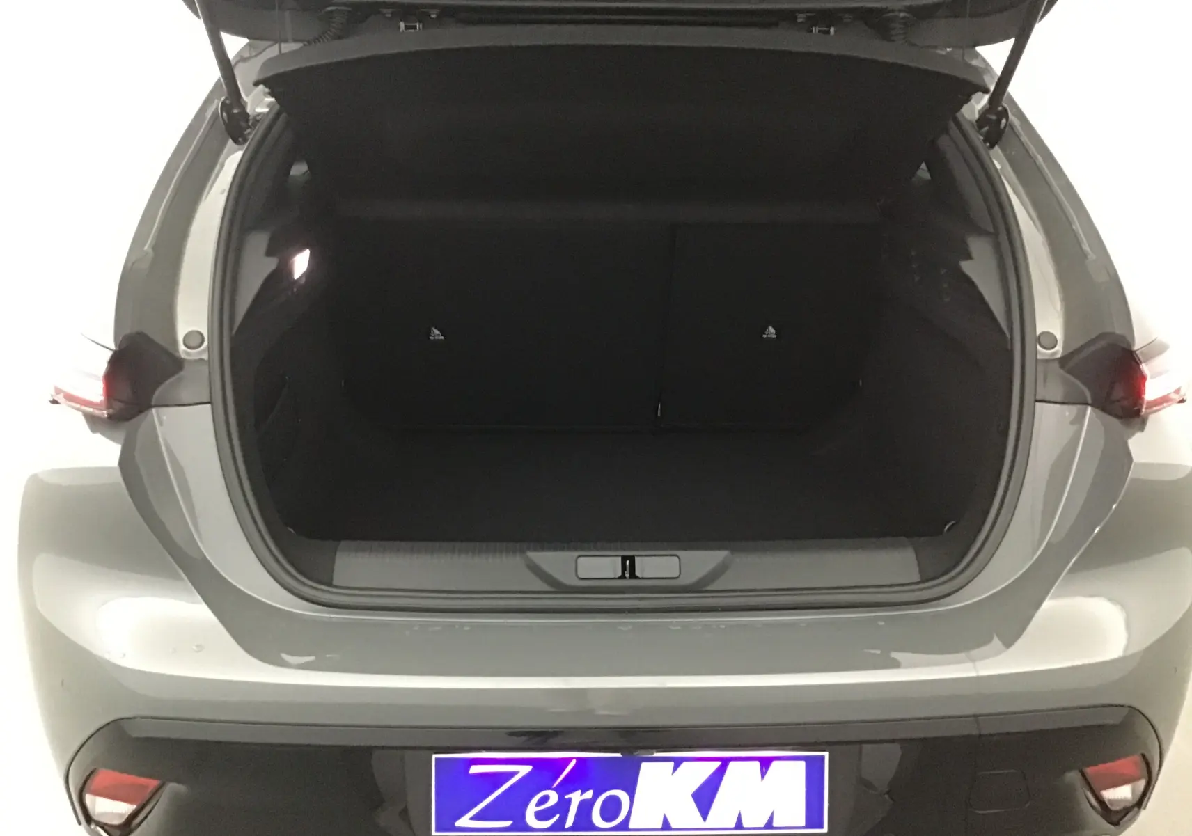 Coffre ouvert vu de l'arrière d'une Peugeot 308 gris Sellenium, montrant l'espace de chargement vide.