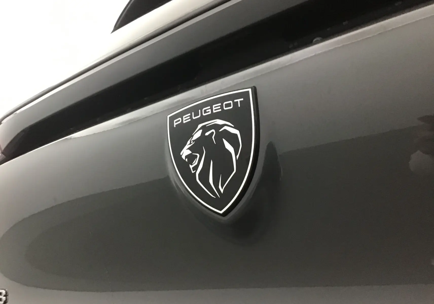 Gros plan sur l'écusson Peugeot noir et blanc sur la malle arrière gris Sellenium de la 308 2025.