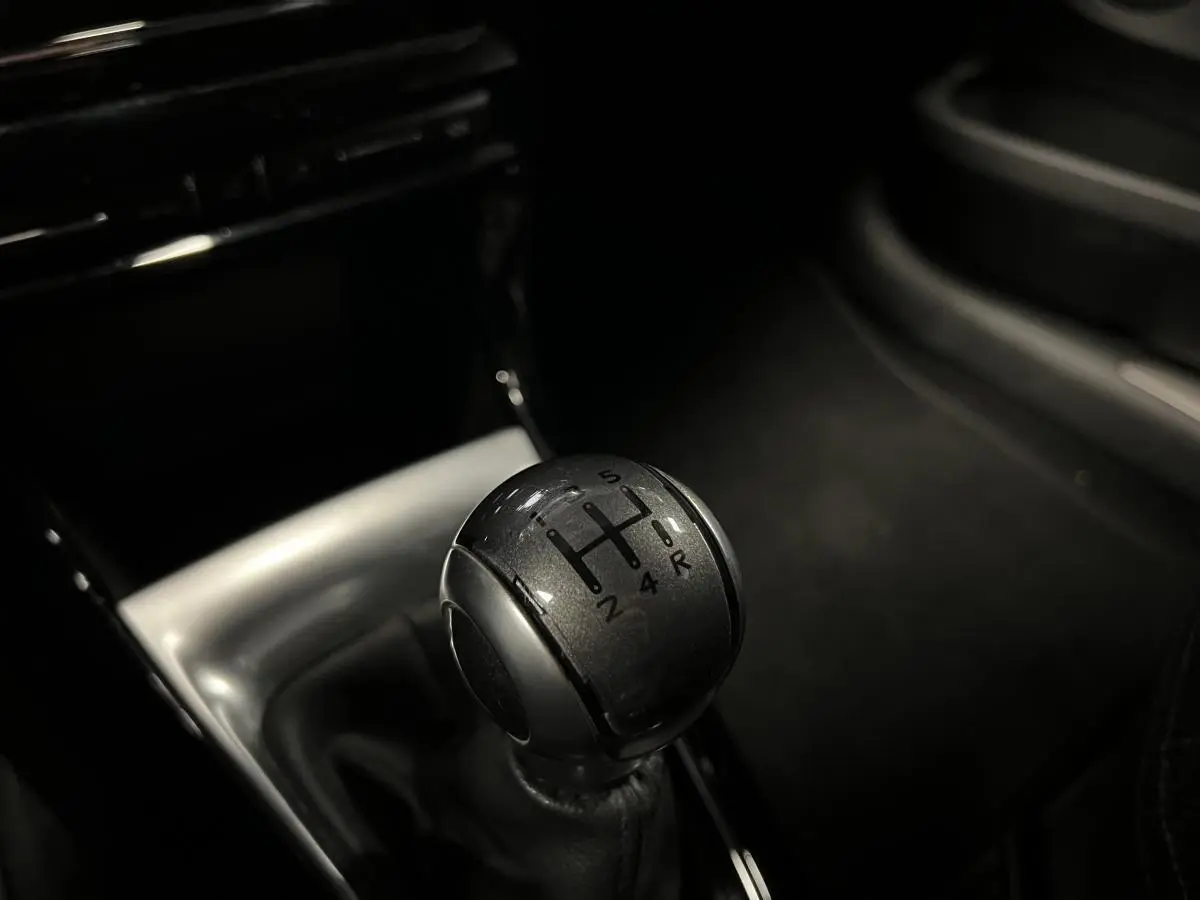 Gros plan sur le levier de vitesses manuel noir du DS3 violet, avec console centrale brillante en arrière-plan.