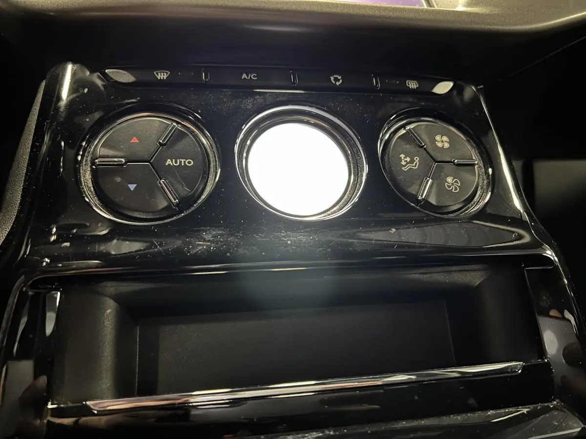 Gros plan sur les commandes de climatisation noire brillante du tableau de bord de la DS3 violet 2016.