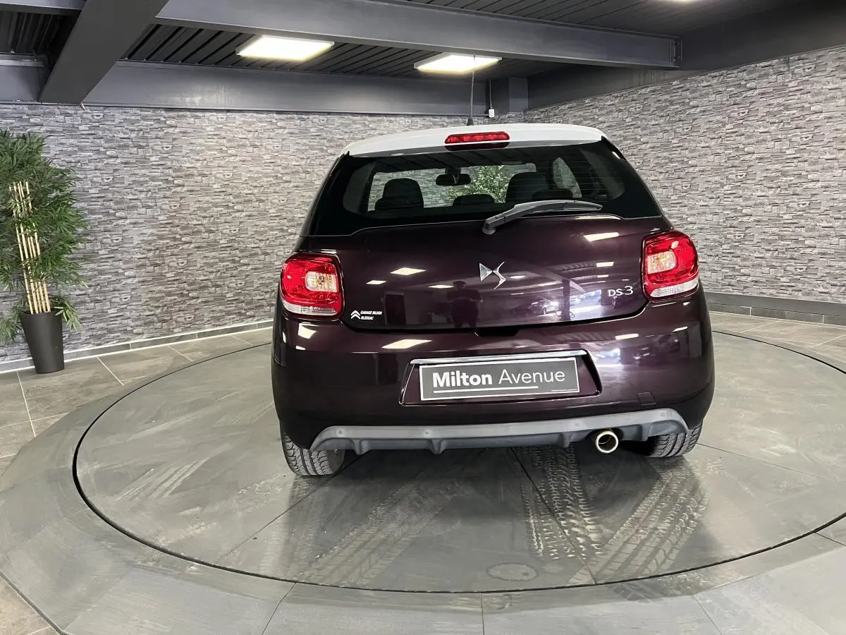 Vue arrière d'une DS3 violet foncé avec toit blanc, feux LED et canule d'échappement chromée visible en intérieur.