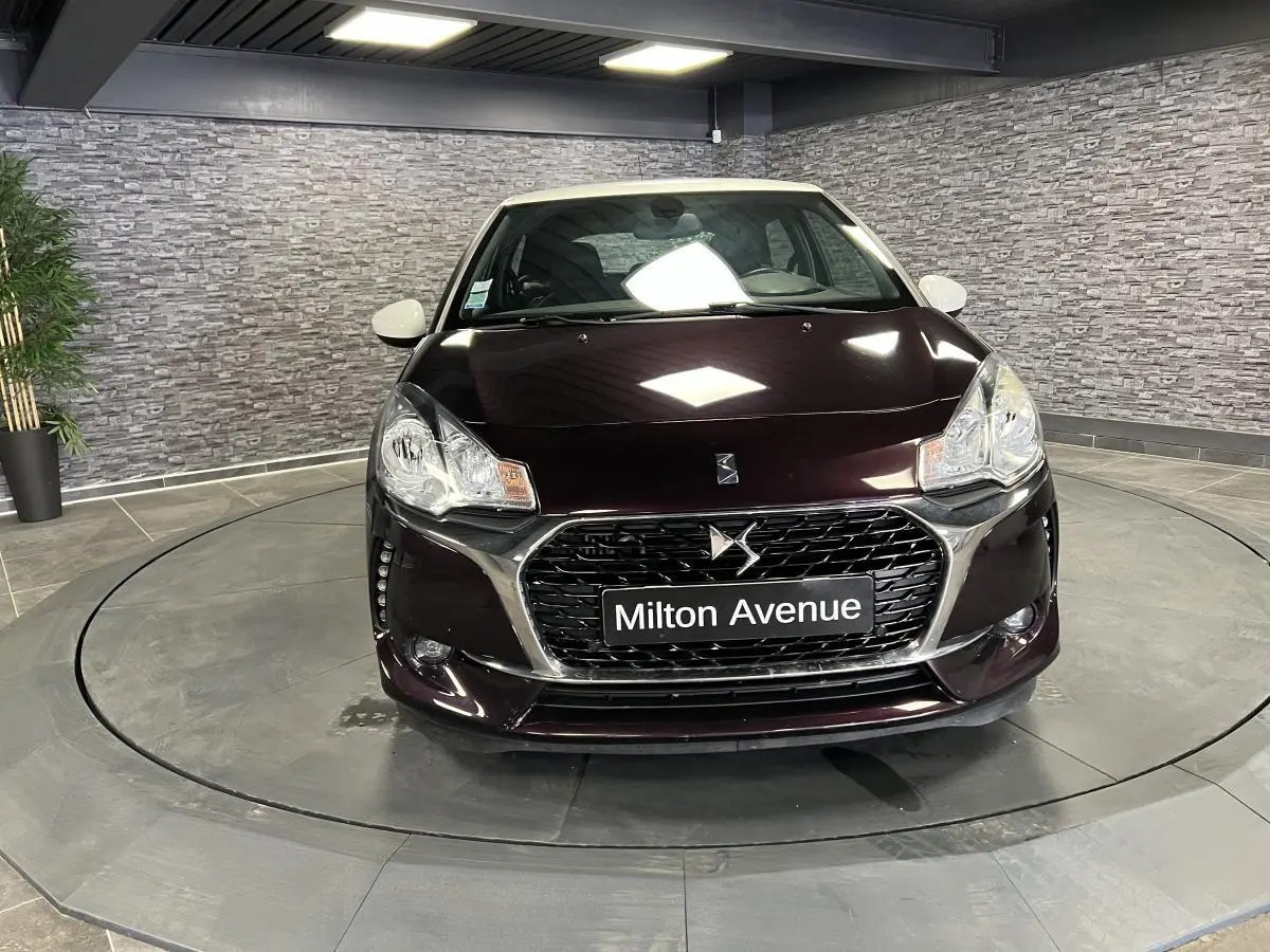 Vue frontale d'une DS3 violet foncé avec calandre chromée et plaque Milton Avenue en showroom.