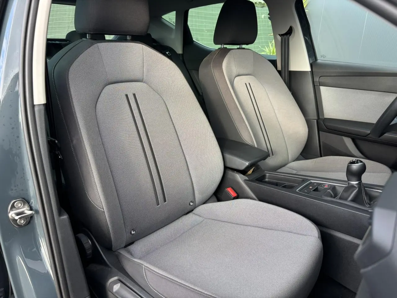 Vue intérieure côté conducteur du SEAT Leon 2.0 TDI 115 Style 2025, sièges gris et levier de vitesses manuel visible.