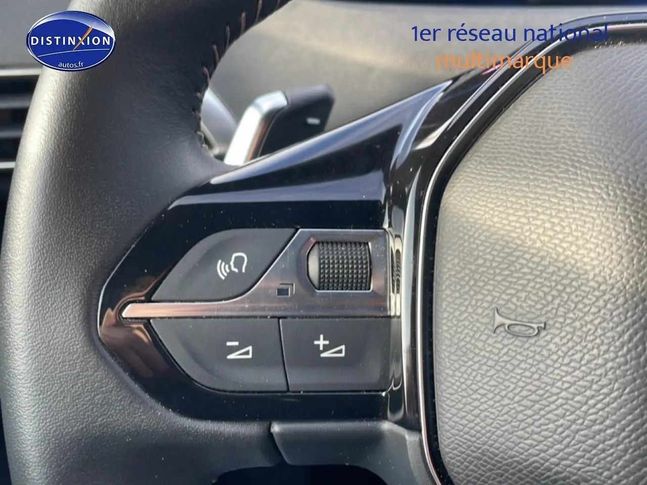 Gros plan sur les commandes vocales et volume au volant cuir du Peugeot 3008 bleu plug-in hybrid 2024.