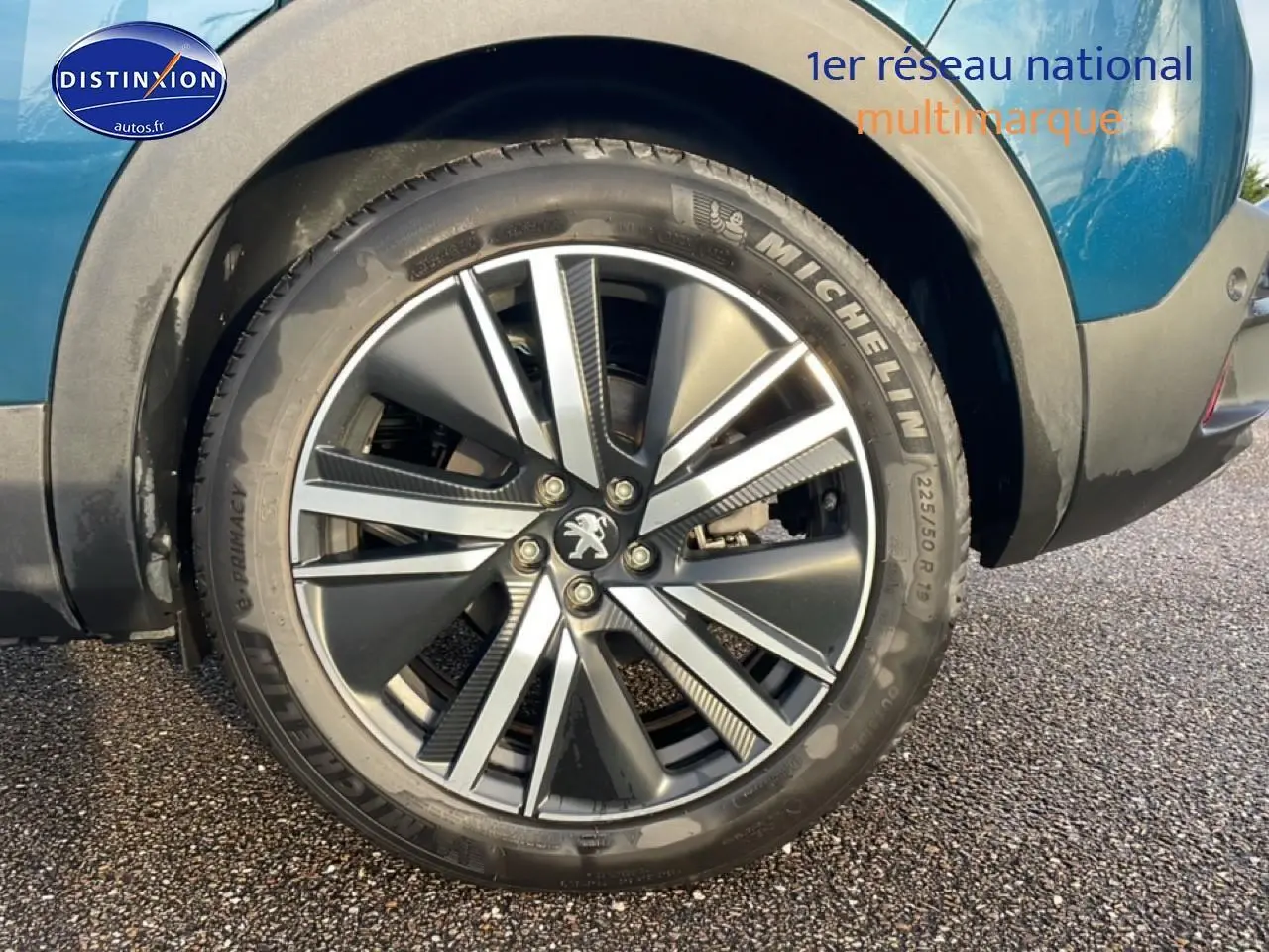 Gros plan sur la roue avant droite avec jante alu bicolore du Peugeot 3008 bleu 2024 plug-in hybrid.