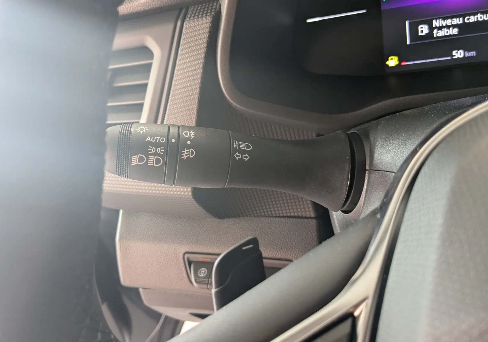 Gros plan sur la commande des feux et clignotants à gauche du volant dans le Renault Trafic Cabine Approfondie gris comète 2025.