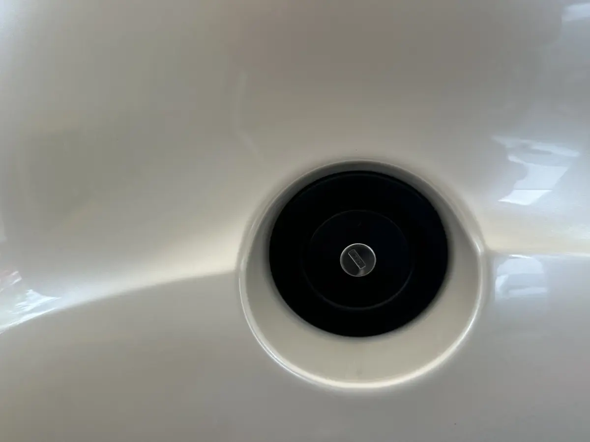 Gros plan sur la trappe de réservoir noir intégrée dans la carrosserie blanche de l'AIXAM AMBITION 0.5 CROSSOVER PREMIUM.