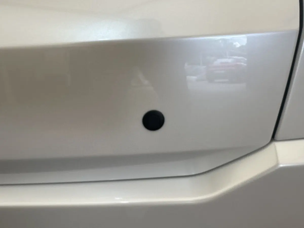 Gros plan sur la carrosserie blanche de l'AIXAM AMBITION 0.5 CROSSOVER PREMIUM, montrant un capteur noir intégré.