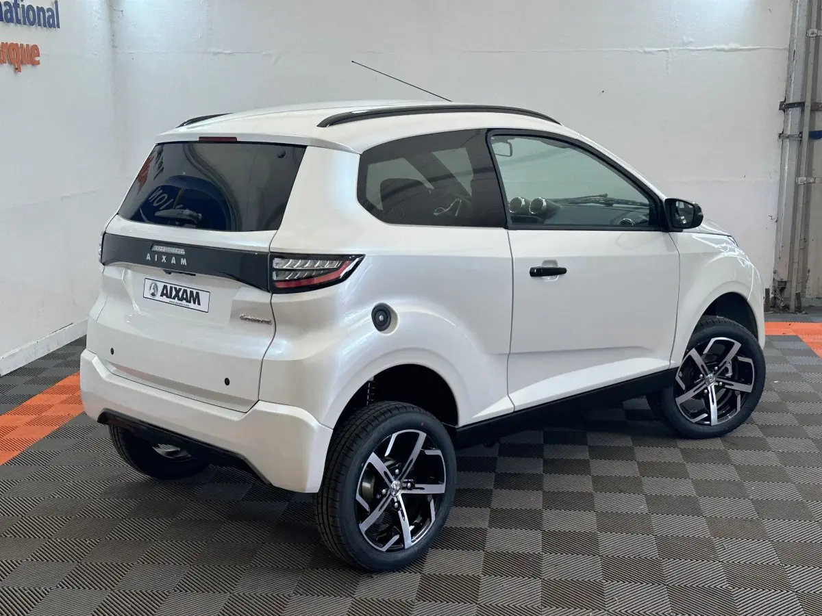 Vue 3/4 arrière droite d'une Aixam Ambition 0.5 Crossover Premium blanche avec rétroviseur caméra côté conducteur.