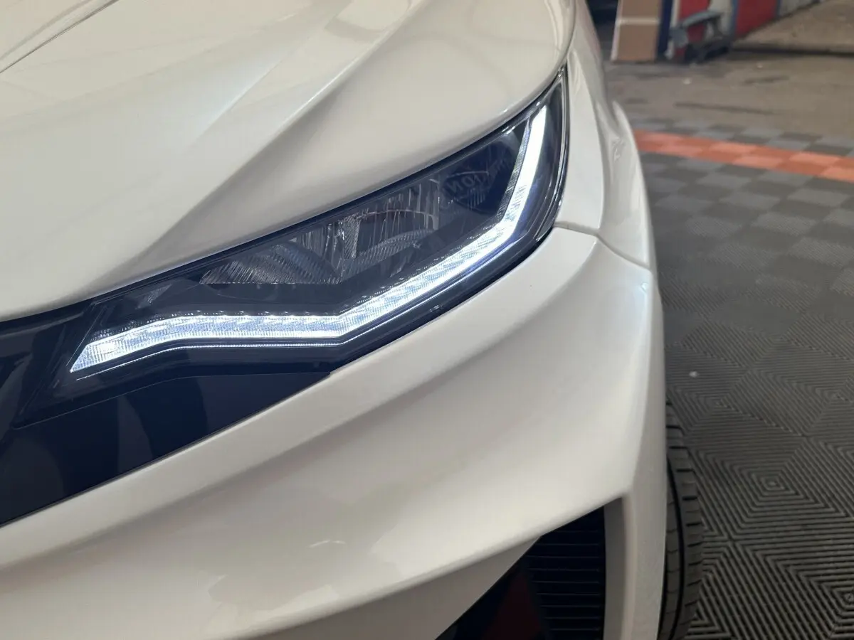 Gros plan sur le phare avant droit blanc de l'AIXAM AMBITION 0.5 CROSSOVER PREMIUM avec éclairage LED distinctif.