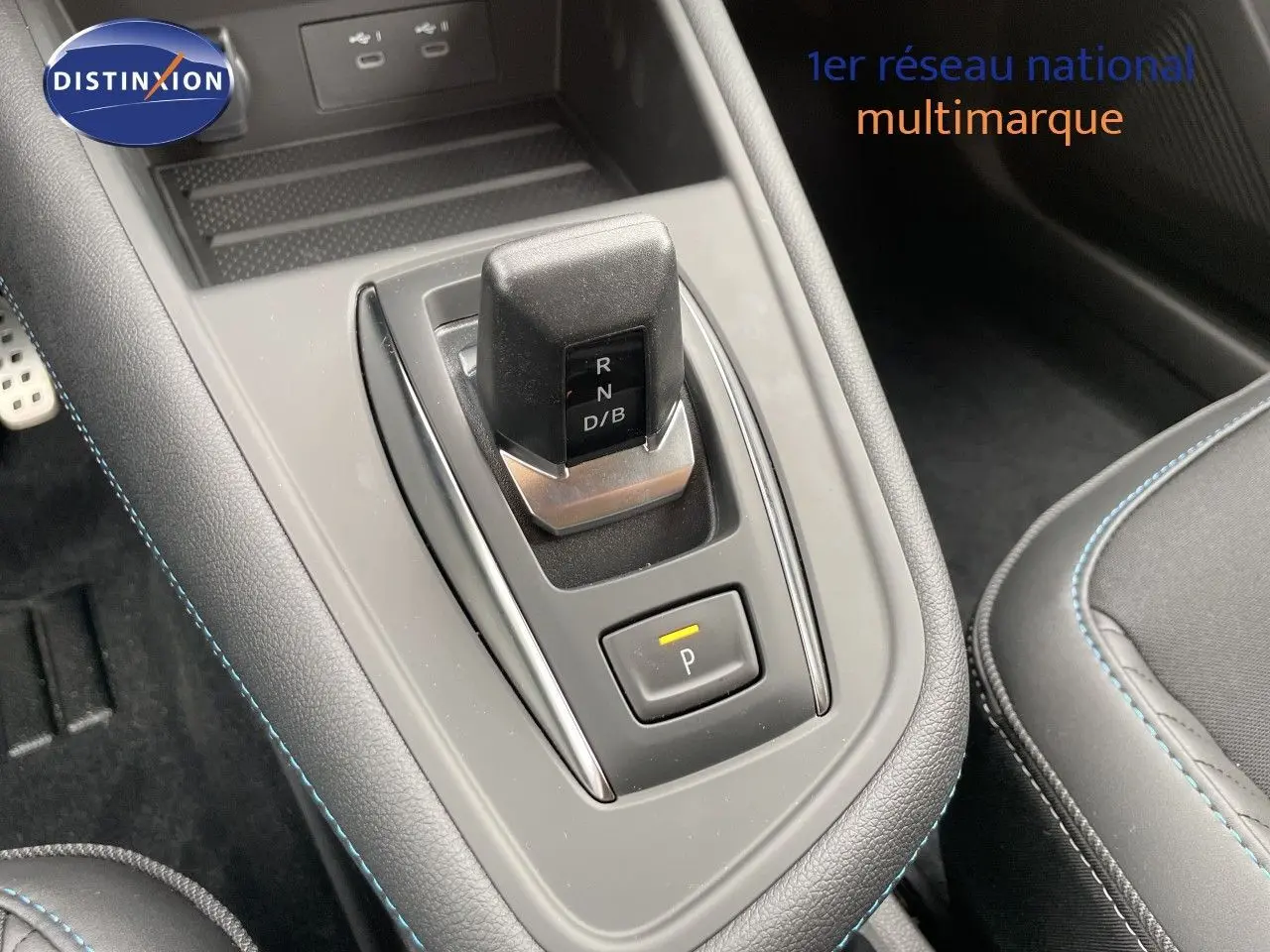 Vue rapprochée de la console centrale grise avec levier de vitesses automatique et bouton de parking éclairé dans Renault Symbioz gris cassiopée.