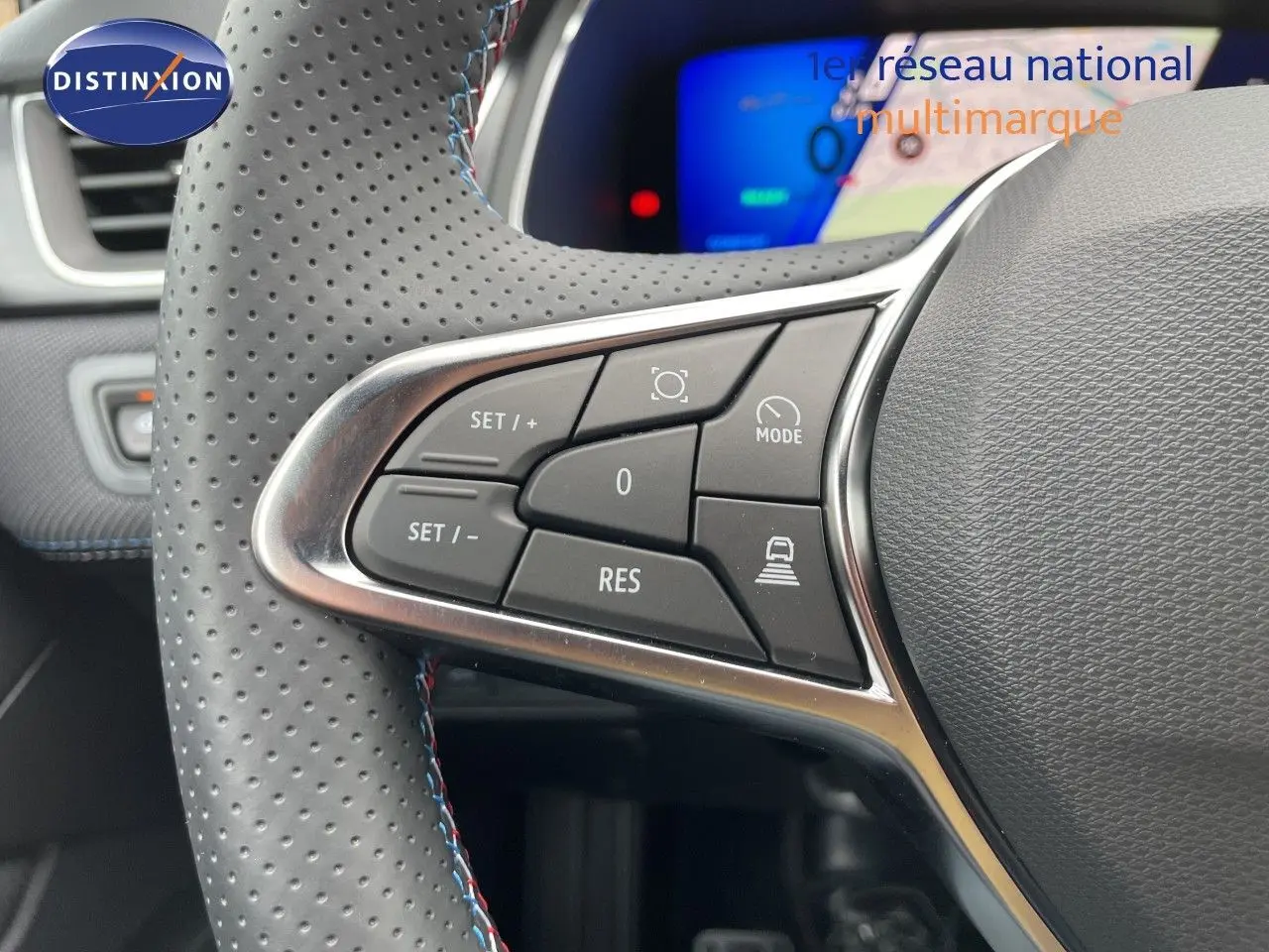 Gros plan sur les commandes à gauche du volant perforé gris du Renault Symbioz 2026, avec tableau de bord numérique en arrière-plan.