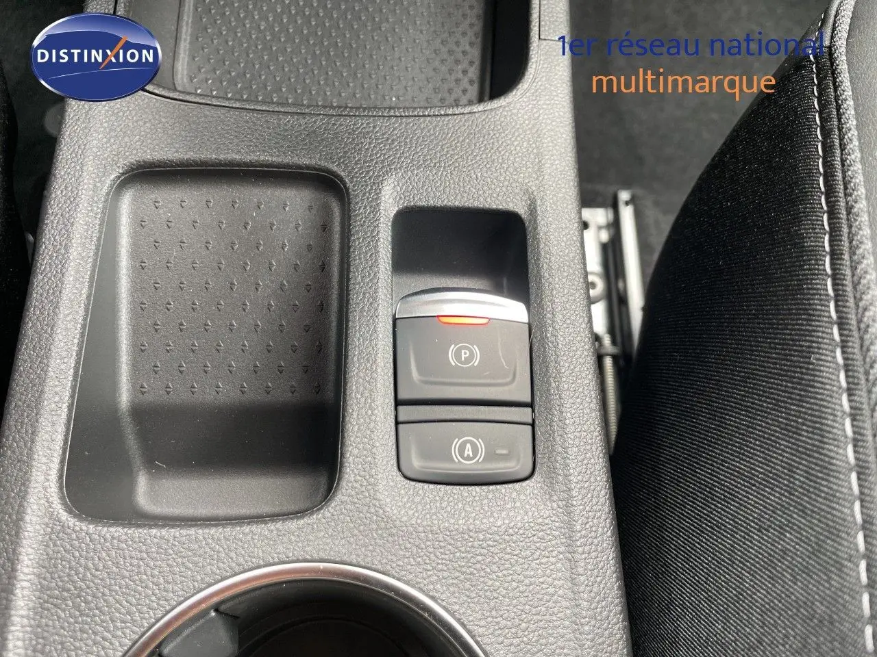 Gros plan sur la console centrale noire avec boutons de frein à main et arrêt automatique de la Renault Symbioz gris cassiopée.