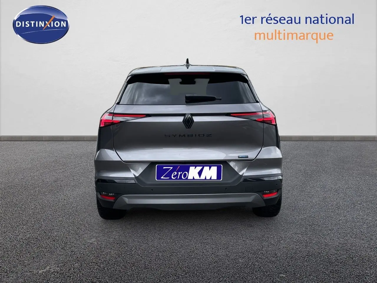 Vue arrière d'une Renault Symbioz gris cassiopée métal, avec feux arrière fins et plaque Zero KM visible.