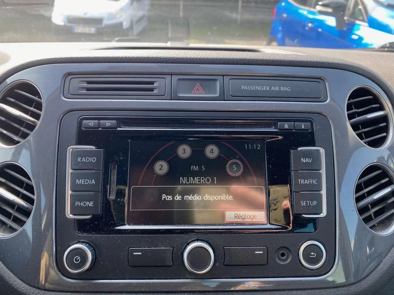 Gros plan sur l'écran multimédia central du Volkswagen Tiguan blanc de 2014 avec commandes radio et navigation visibles.