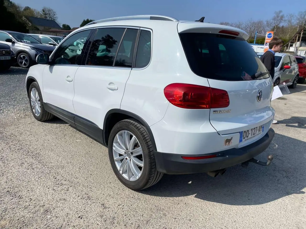 Vue 3/4 arrière droite d'un Volkswagen Tiguan blanc 2014 avec attelage et vitres arrière surteintées.