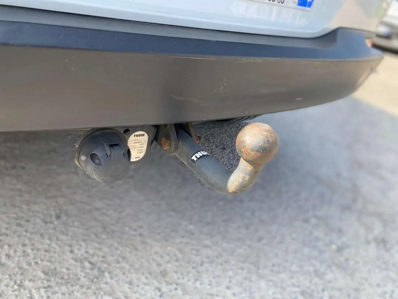 Gros plan sur l'attelage arrière rouillé du Volkswagen Tiguan blanc de 2014 avec prise électrique intégrée.