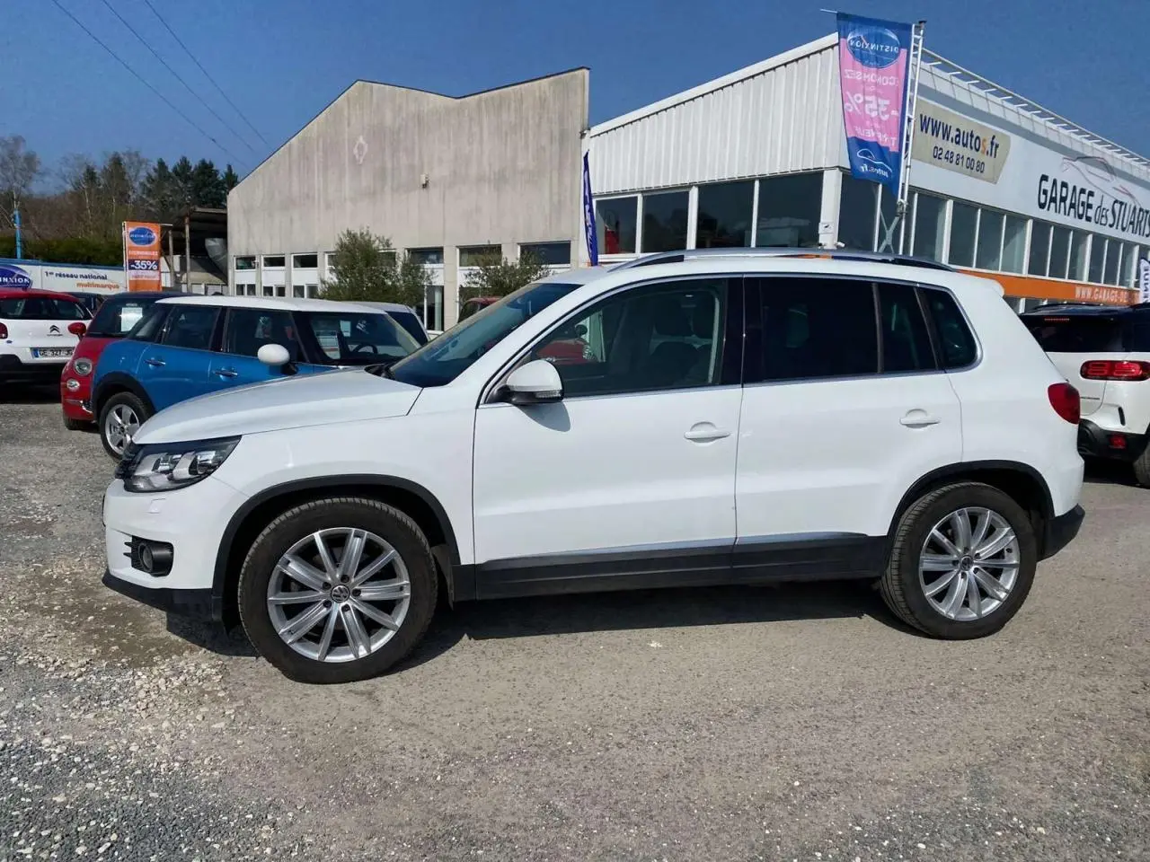 Volkswagen Tiguan blanc vu de profil côté gauche, avec jantes alliage 18 pouces et caméra de recul visible.