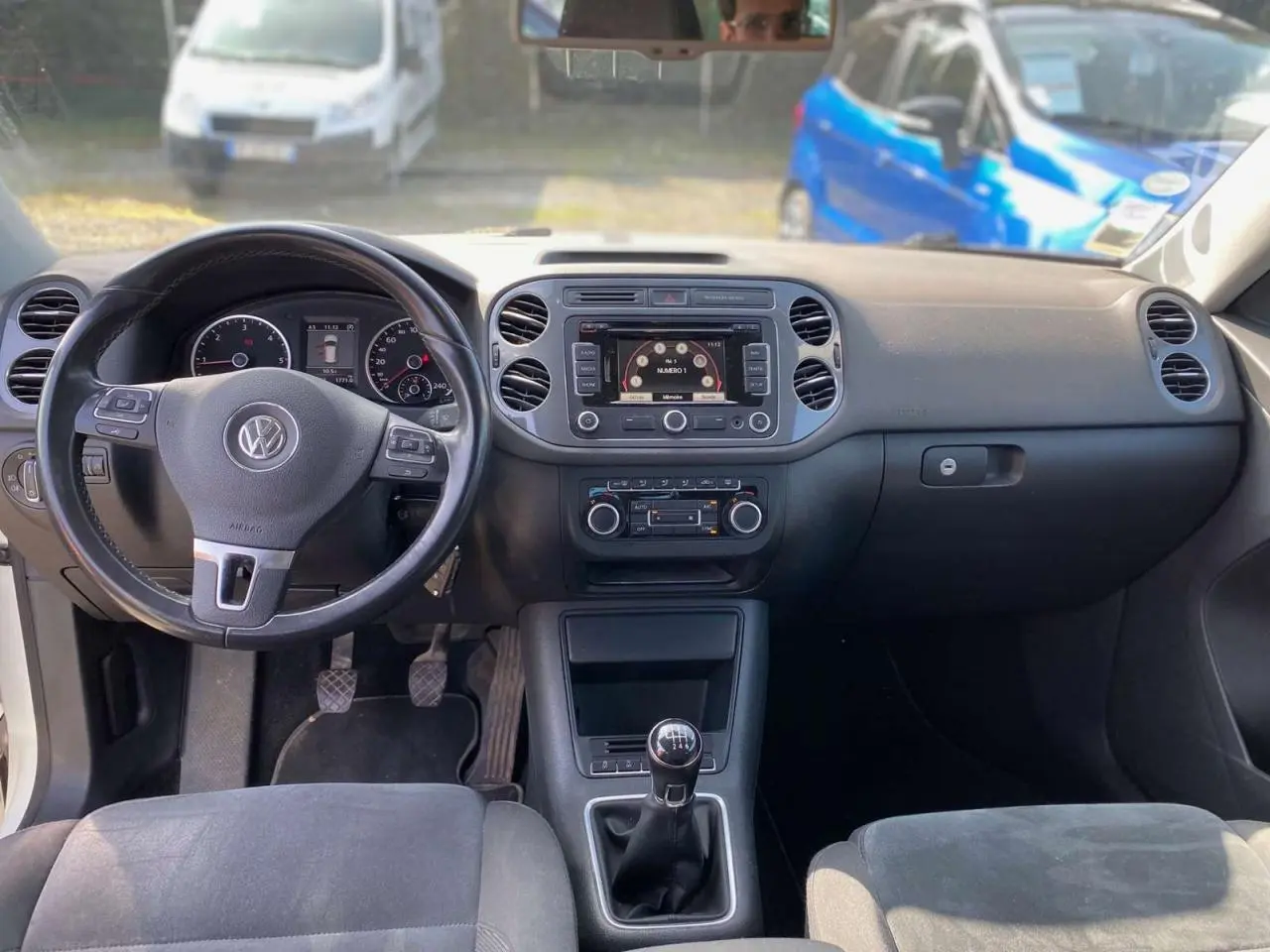 Vue intérieure du tableau de bord et volant cuir multifonction du Volkswagen Tiguan blanc avec boîte manuelle.