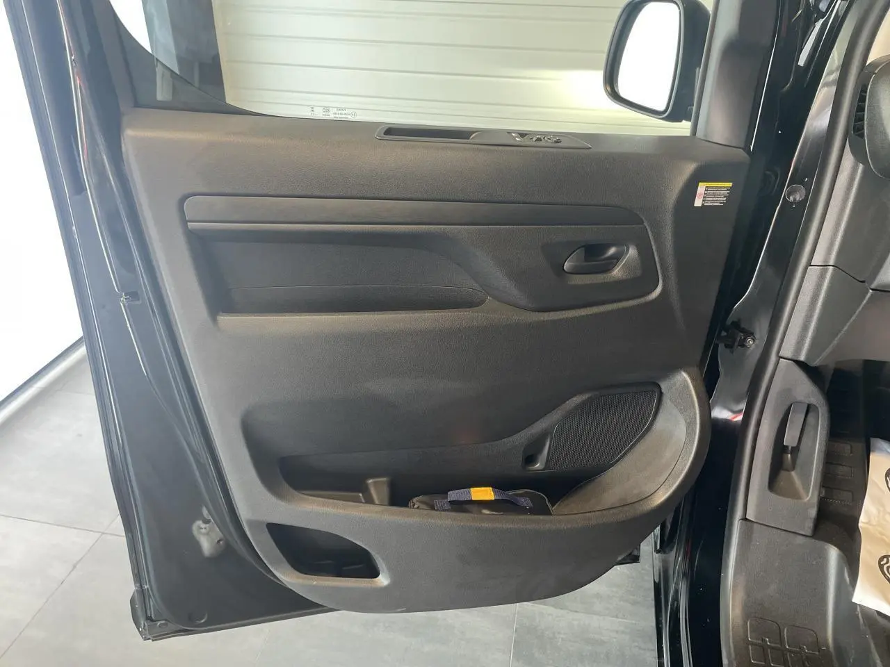 Vue rapprochée de la porte avant gauche noire carbone de l'Opel Vivaro 2025 avec poignée et rangement intégré.