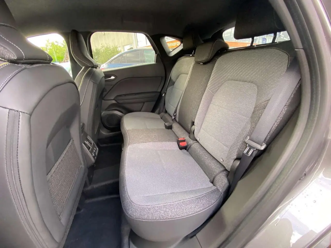 Vue intérieure sur la banquette arrière grise du Renault Captur 2025, avec ceintures et appuis-tête visibles.