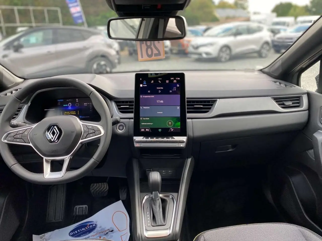 Vue intérieure frontale du tableau de bord du Renault Captur 2025 avec écran tactile vertical et volant multifonction.