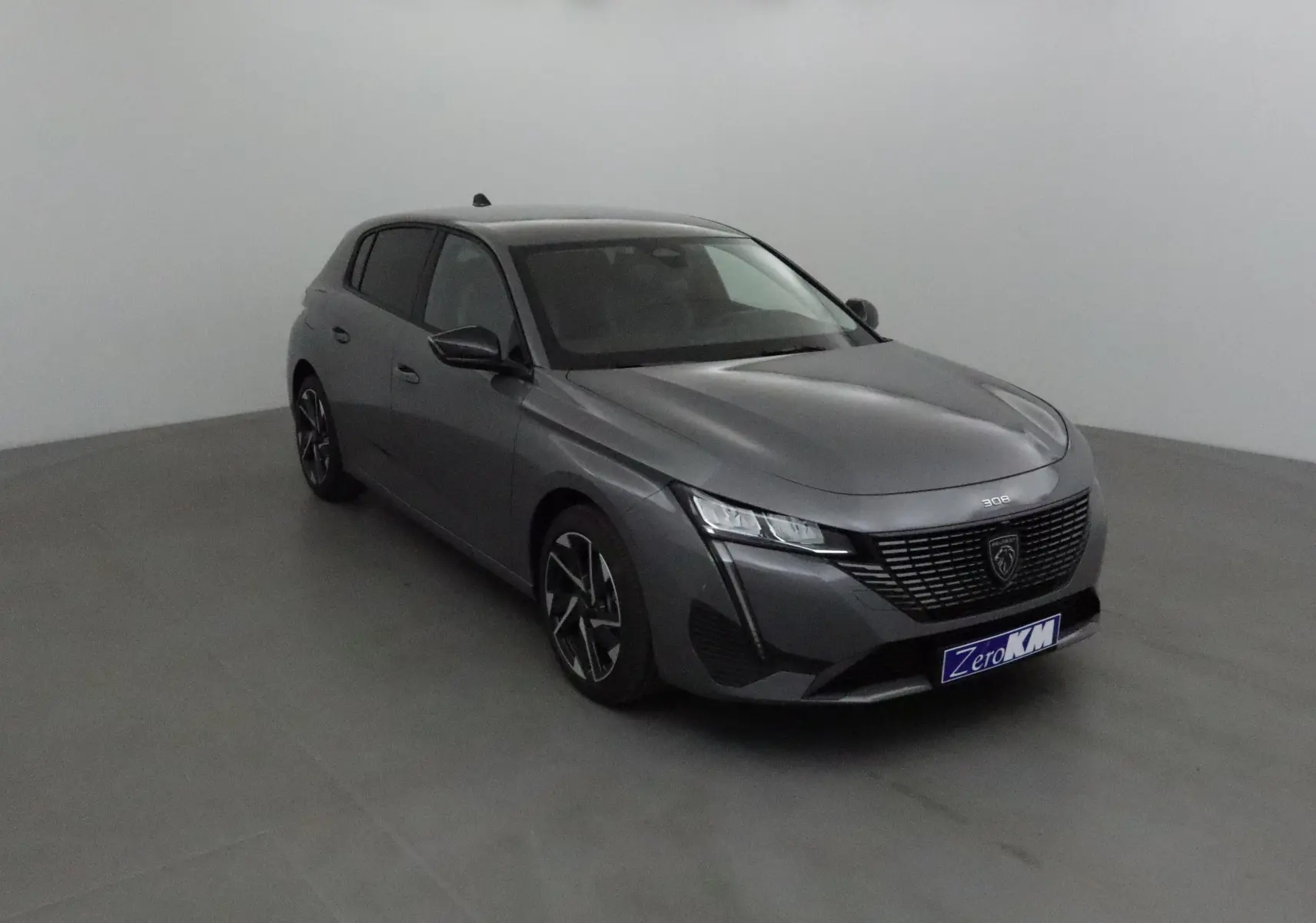Peugeot 308 gris Sellenium vue 3/4 avant droit avec calandre noire et jantes alliage modernes.