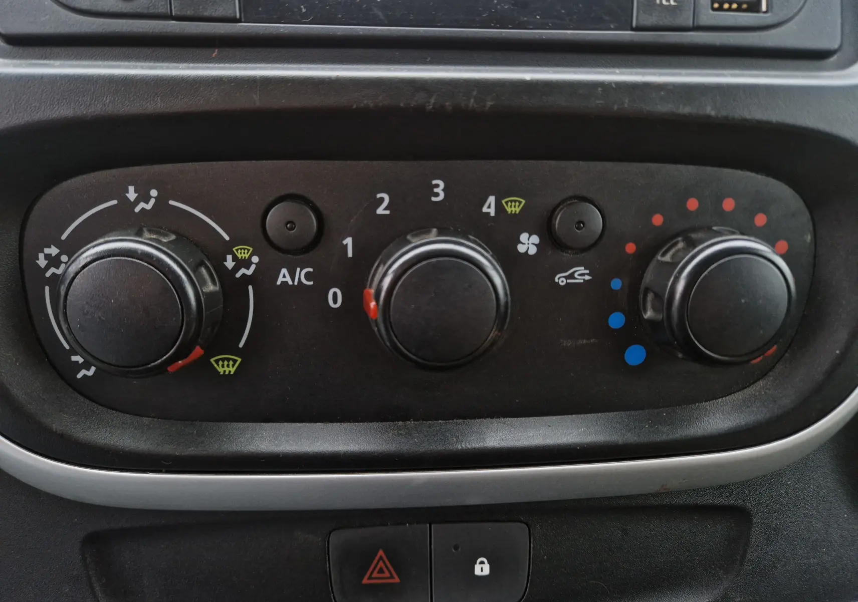 Panneau de commande de climatisation noir dans un Renault Trafic Fourgon blanc, vue rapprochée du tableau de bord.