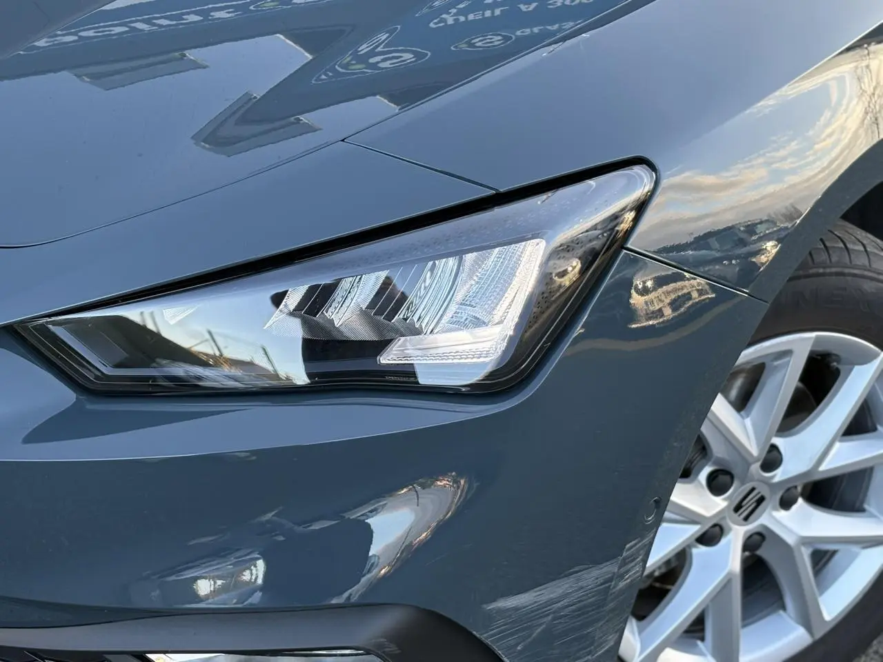 Gros plan sur le projecteur avant gauche et la jante alliage 16 pouces d'une SEAT LEON ST Bleu Fjord 2025.