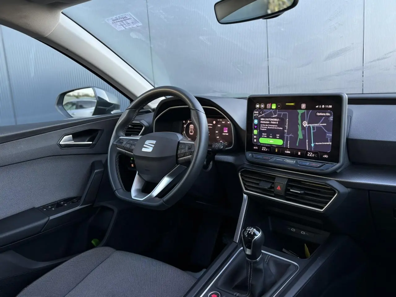 Vue intérieure côté conducteur du SEAT LEON ST 2.0 TDI 115 Style 2025, volant cuir multifonction et écran tactile central.