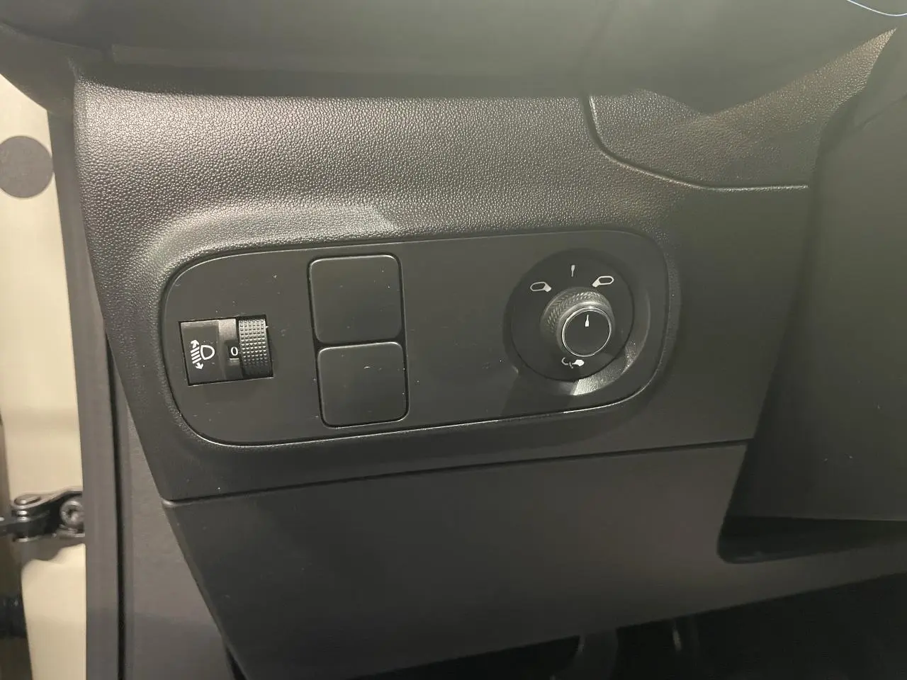 Vue intérieure côté gauche de la porte beige clair d'une Citroën C3 2024 avec commandes de réglage des rétroviseurs et phares.