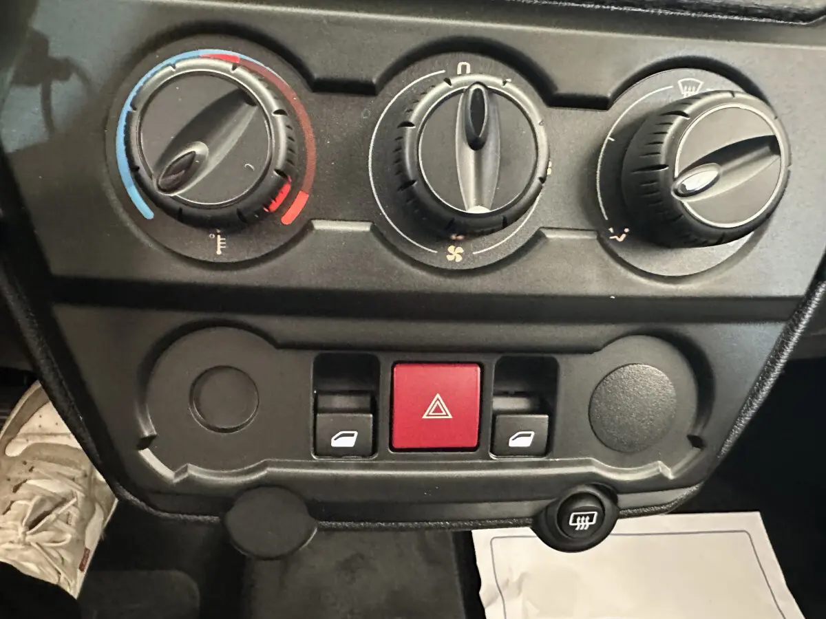 Gros plan sur les commandes de climatisation et les boutons de l’AIXAM AMBITION 0.5 CITY PACK 2026, tableau de bord noir.